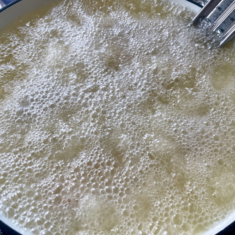 Image of When the oil reaches 350°F, knock off the excess flour on 4 pieces and lay them gently, skin side down, in the pan of oil. Make sure not to add too much chicken at once as you want to keep...